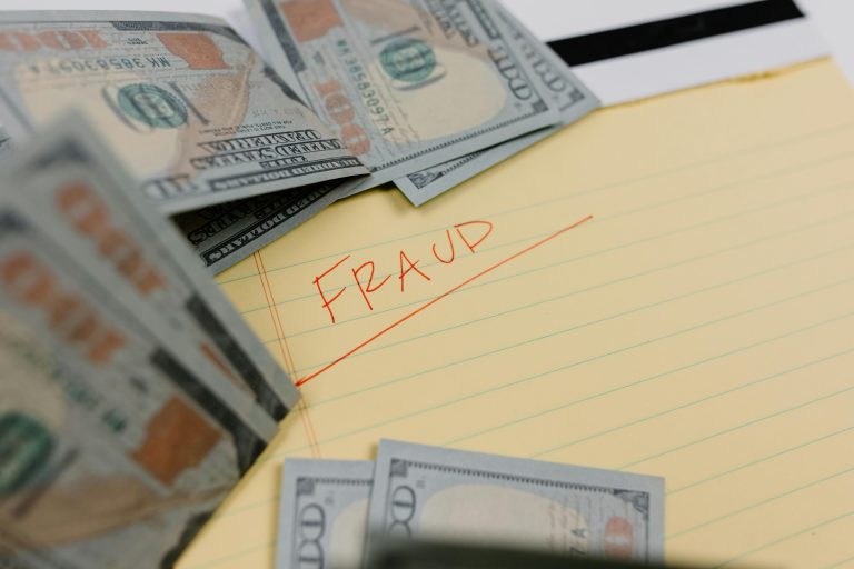 Money surrounding a note labeled 'FRAUD'